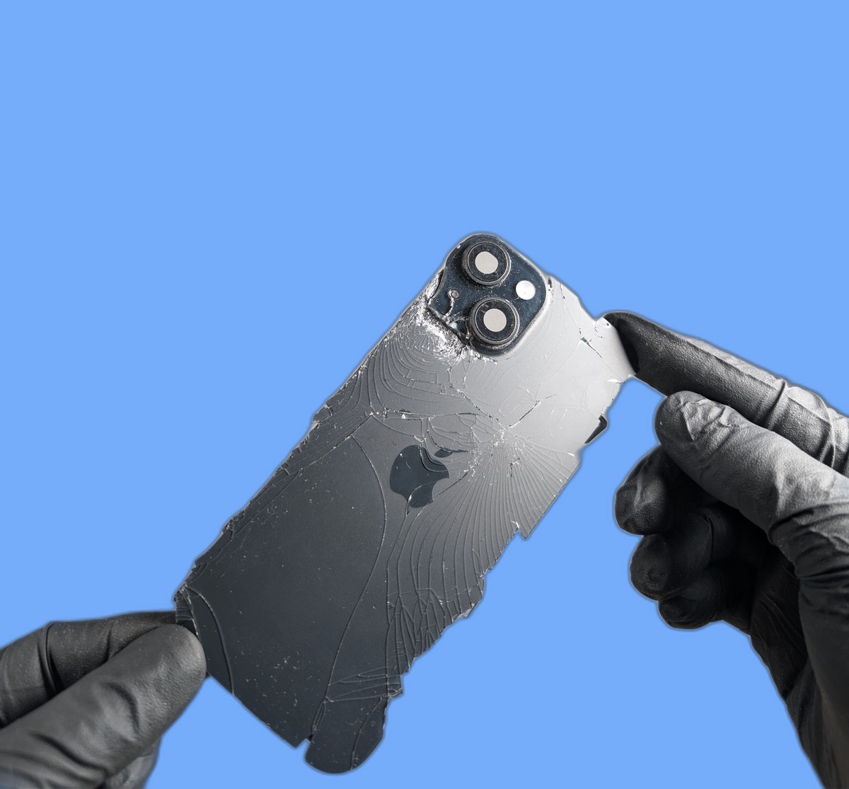 Cracked iPhone back glass being held by technician in black repair gloves
